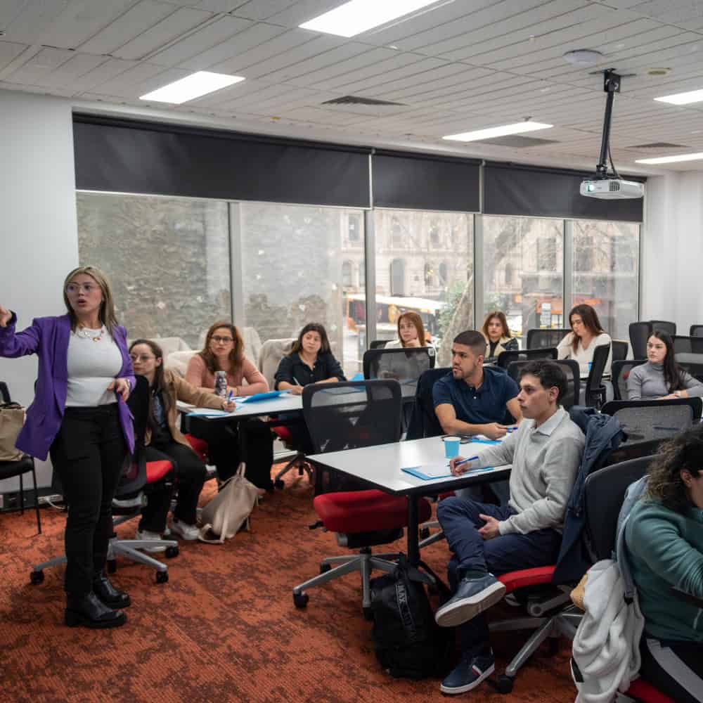 Cristina Carvajal impartiendo una charla en un aula moderna con estudiantes atentos.